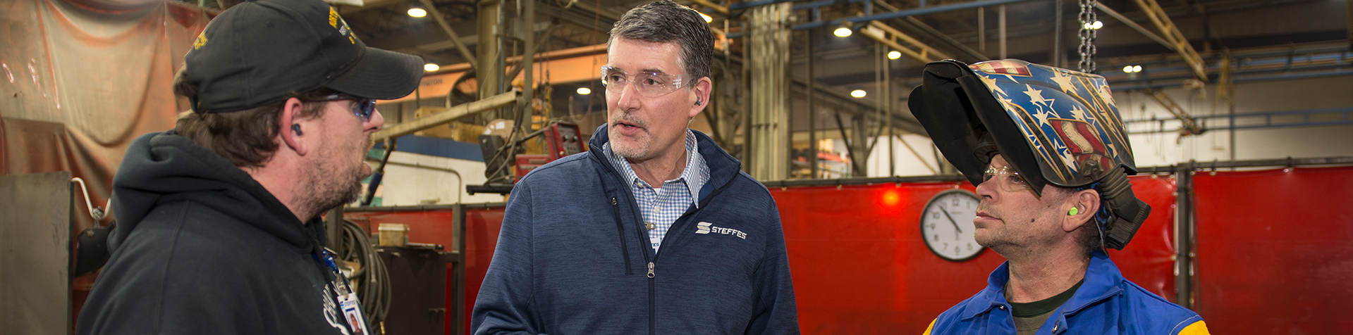 Paul Eidenschink talking to two Steffes employees on the manufacturing plant floor